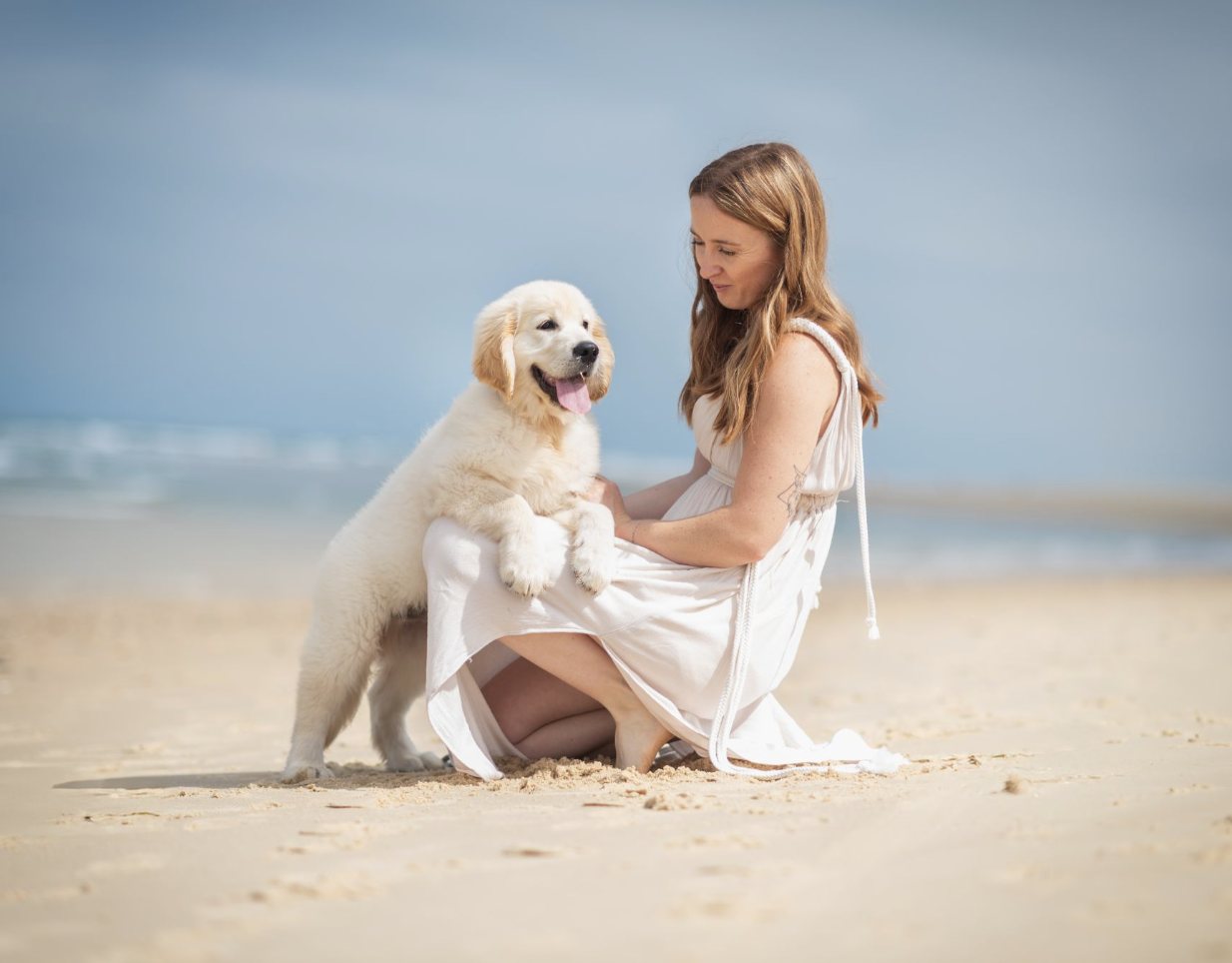 Jeune femme et son chiot golden retriever sur la plage